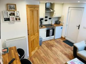 Mc Courts Barn, Tiny house in the Mournes في Hilltown: مطبخ صغير مع دواليب بيضاء وارضية خشبية