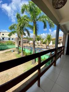 a balcony with a view of a pool and palm trees at POUSADA TAIEIRAS in Maragogi