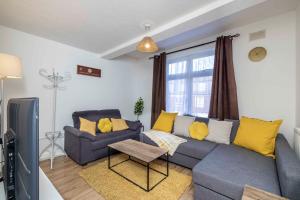 a living room with a blue couch and yellow pillows at Charming 3-Bed Townhouse in Vibrant Ealing in Ealing