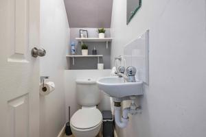 a white bathroom with a toilet and a sink at Charming 3-Bed Townhouse in Vibrant Ealing in Ealing