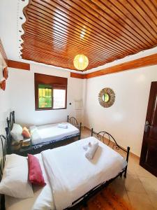 a bedroom with two beds and a wooden ceiling at Olympe Surf & Yoga in Tamraght Ouzdar