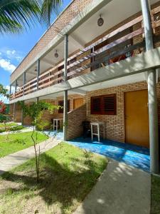 a building with a balcony and a table in a yard at POUSADA TAIEIRAS in Maragogi