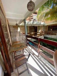 a porch with a wooden bench and a chair at POUSADA TAIEIRAS in Maragogi