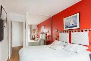 a bedroom with a white bed with red walls at Eiffel Tower Elegant Residence in Paris