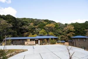 um edifício com uma montanha ao fundo em 横川温泉湯殿ととのゆ em Shimoda