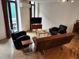 Una sala de estar con un sofá y sillas y un televisor. en Ulysses Apartments Monastiraki, en Atenas