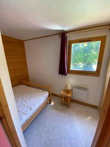 a small bedroom with a bed and a window at Chalet nordique 31 in La Féclaz