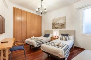 a bedroom with two beds and a desk and a table at San Mames Apartment - Free Parking in Bilbao
