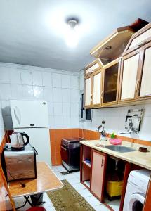 a kitchen with wooden cabinets and a white refrigerator at شقة مفروشة لك وحدك قريبة من مكتبة الاسكندرية in Alexandria