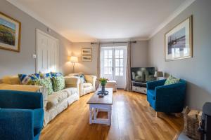 a living room with two couches and a tv at Mahonia Cottage in Burnham Market