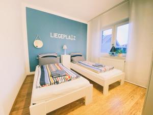 two beds in a room with a blue wall at Ferienhaus Nordlicht in Geeste