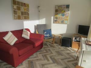 a living room with a red couch and a television at Coastal Glow in Heacham