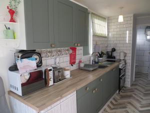 a kitchen with gray cabinets and a wooden counter top at Coastal Glow in Heacham