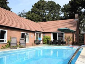 uma casa com uma piscina com cadeiras e um guarda-sol em 5 Bed in Woodbridge 72724 em Woodbridge