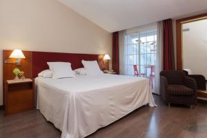 a bedroom with a large white bed and a chair at URH Ciutat de Mataró in Mataró