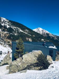 a building in the snow next to a mountain at Cabin on a Rock - Mountain Escape in Deçan