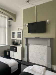 a room with two beds and a flat screen tv on the wall at Holiday Plus - Holmfield Road in Blackpool