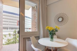 een eetkamer met een tafel en een vaas met bloemen bij San Mames Apartment - Free Parking in Bilbao