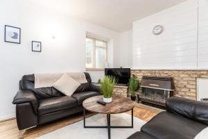 a living room with a leather couch and a fireplace at April Disc - Long Stay - Contractors in Swindon