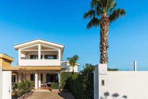 un palmier devant une maison blanche dans l'établissement Dimore Anny, à Reitani