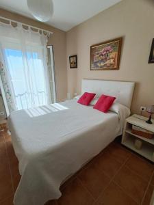 - une chambre avec un grand lit blanc et 2 oreillers rouges dans l'établissement Primera línea de playa en Canela Park, à Isla Canela