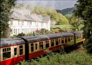 a train on the tracks in front of a house at Steam Train Cottage - Lake District Hideaway in Newby Bridge