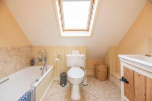 a bathroom with a toilet and a tub and a sink at 3 Old School Cottages, Wissett in Halesworth