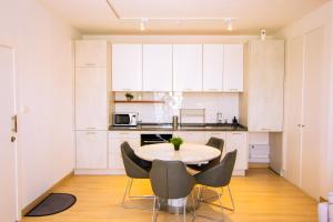 a kitchen with white cabinets and a table and chairs at The Pavilion 1BDR Luxury Apt in Accra