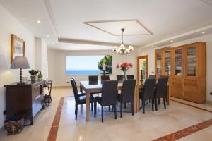 una sala da pranzo con tavolo, sedie e vista sull'oceano di Villa Cab - Cala Vinyas a Cala Vinyes