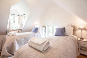 a bedroom with two beds with white and blue pillows at 3 Old School Cottages, Wissett in Halesworth