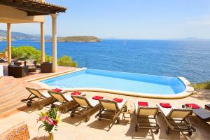 una piscina con sedie e vista sull'oceano di Villa Cab - Cala Vinyas a Cala Vinyes