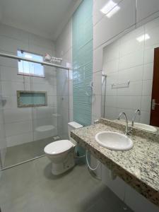 y baño con aseo, lavabo y ducha. en Casas Amarelas II - Prado BA en Guarani