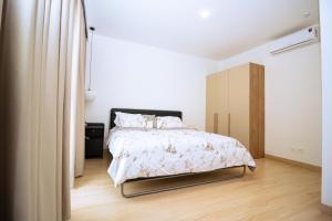 a white bedroom with a bed and a wooden floor at The Pavilion 1BDR Luxury Apt in Accra