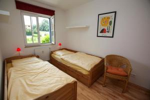 two beds in a room with a chair and a window at Landhaus Kaiser zum Strande - b47256 in Bastorf