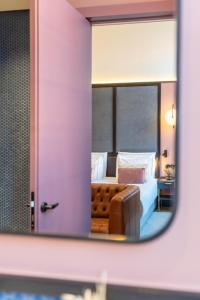 specchio che riflette una camera con letto e divano. di The Editory Riverside Hotel, an Historic Hotel a Lisbona