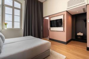 a hotel room with a bed and a flat screen tv at The Editory Riverside Hotel, an Historic Hotel in Lisbon