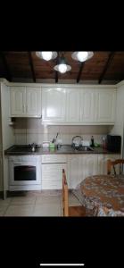 a kitchen with white cabinets and a sink and a table at Casa rural entre la naturaleza Gomera in El Cercado
