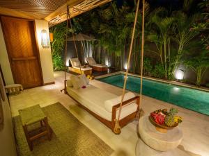 a bedroom with a swinging bed and a swimming pool at Cocana Resort Gili Trawangan in Gili Trawangan