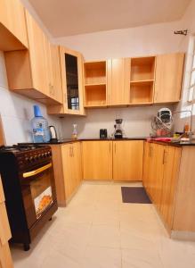 a kitchen with wooden cabinets and an oven at Rossyln Home close to Village Market, UN and Two Rivers Mall in Nairobi