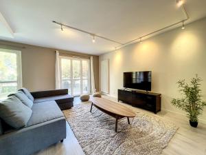 a living room with a couch and a flat screen tv at Hamac Suites - Docteur Terver - 6 people in Écully