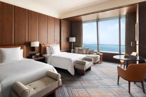 大連市にあるFour Seasons Hotel Dalianのベッド2台とテーブルが備わるホテルルームです。