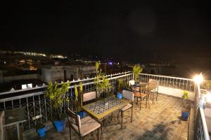 a patio with tables and chairs on a balcony at night at Riad Dar Rabha in Fez