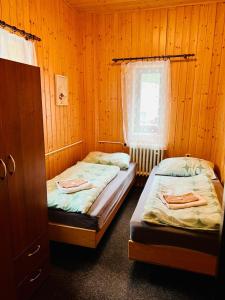 two beds in a room with wooden walls at Bouda Bílé Labe in Špindlerův Mlýn
