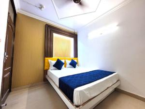 a bedroom with a bed with blue and yellow pillows at HOTEL ANCHAL DX in New Delhi