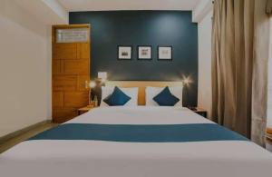 um quarto com uma grande cama branca com almofadas azuis em HOTEL ANCHAL DX em Nova Deli