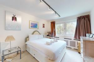 a bedroom with a large white bed and a window at Gorgeous 2 bed flat with free parking and garden in London