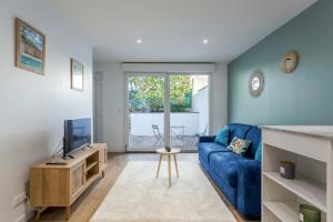 ein Wohnzimmer mit einem blauen Sofa und einem TV in der Unterkunft Hamac Suites - Le Valdo - 2 pers in Lyon