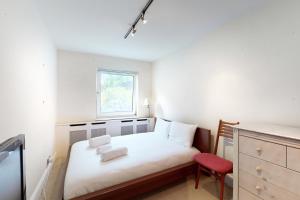 a small bedroom with a bed and a red chair at Gorgeous 2 bed flat with free parking and garden in London