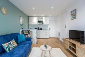 ein Wohnzimmer mit einem blauen Sofa und einer Küche in der Unterkunft Hamac Suites - Le Valdo - 2 pers in Lyon