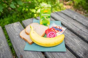 a banana and a sandwich and a drink on a picnic table at Juliusskogen 